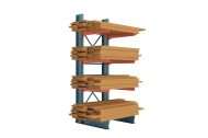 Lumber storage rack with blue uprights and orange arms fully loaded with stacks of wood and lumber.